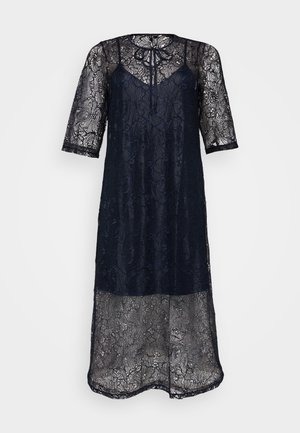 Tamnoplava čipkana haljina s kratkim rukavima, s vezanjem oko vrata i složenim cvjetnim uzorcima. Prozirna tkanina za slojeviti efekt.