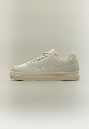 Baskets beige en cuir à profil bas avec lacets, panneaux texturés et semelle épaisse en caoutchouc sur fond beige uni.