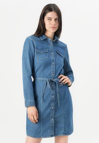 Denim skjortekjole i lyseblått med lange ermer, knappestolpe foran, to brystlommer og knyttet midje, med klassisk krage og subtil tekstur.