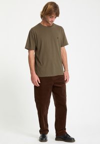 Olive green short-sleeve t-shirt with a round neckline, paired with brown corduroy pants. Black shoes complete the outfit.
