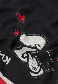 Material textil negru cu un design imprimat care include o mână și inimi roșii, alături de un text stilizat în alb. Textură moale, stil casual.