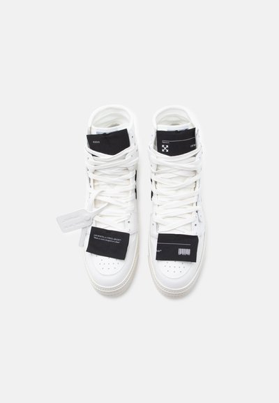 Ein Paar weiße High-Top-Sneaker mit schwarzen Etiketten und Schnürsenkeln, die Text- und Barcode-Details auf einem schlichten hellen Hintergrund aufweisen.