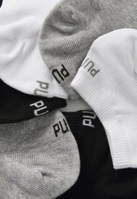 Un set di calze sportive in nero, bianco e grigio. Ogni calza presenta una texture a coste e il logo "PUMA" stampato in colore contrastante sul bordo.