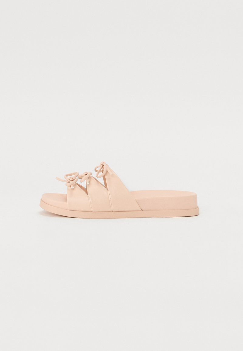 Ροζ σανδάλια με τρία επικαλυπτόμενα λουράκια που διαθέτουν λεπτομέρειες κόμπου, επίπεδη σόλα και λεία υφή. Μινιμαλιστικός σχεδιασμός, ελαφριά κατασκευή.