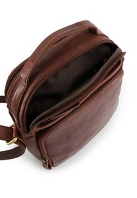 Hnědá kožená crossbody taška s hlavním prostorem a přední kapsou na zip otevřenou, ukazující vnitřní látkovou podšívku a popruh s přezkou.