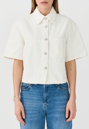 White short-sleeve jacket made from textured fabric, featuring a collar, front buttons, and a chest pocket. Cropped design with frayed hem.