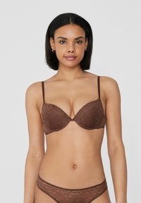Hnědá krajková podprsenka s hlubokým výstřihem, tenkými nastavitelnými ramínky a květinovým vzorem; měkká textura s bezešvými košíčky.