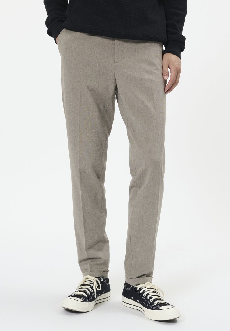 Világosszürke nadrág finom textúrával, egyenes szabással, sima elülső résszel és oldalsó zsebekkel, fekete sportcipővel párosítva.