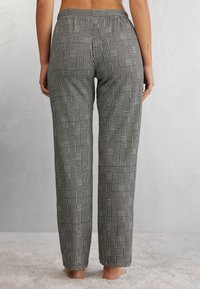 Zwart-wit geblokte broek met een ontspannen pasvorm, elastische tailleband en rechte pijpen, gemaakt van een zachte stof. Geen zichtbare hardware of accenten.