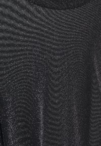 Svart topp med en skimrande struktur, som har ett subtilt vågmönster och rund halsringning. Tyg har en lätt glans och en mjuk framtoning.