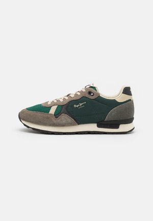 Zapatillas verdes y grises con materiales de ante y malla, diseño con cordones, acentos crema y suela negra. Presenta detalles de logo.