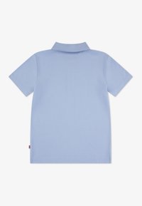 Polo à manches courtes de couleur bleu clair, doté d'un col classique, d'un ourlet droit et d'un design minimaliste sans motifs ni ornements.