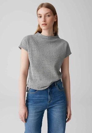 Grijs crop top met korte mouwen en een hoge halslijn, gecombineerd met blauwe high-waisted jeans, weergegeven op een neutrale achtergrond.