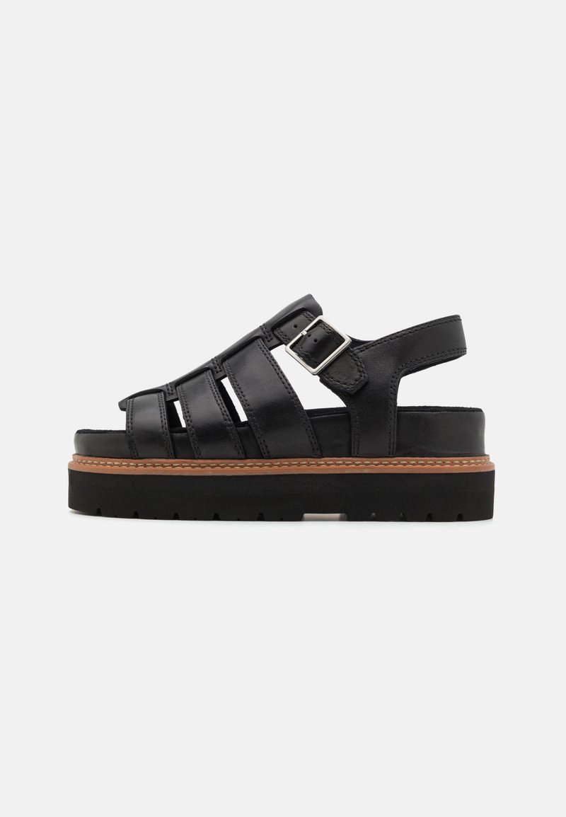Sandale à plateforme en cuir noir avec plusieurs brides horizontales, boucle argentée réglable et semelle épaisse en caoutchouc avec bordure marron.