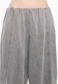Gray denim wide-leg pants with an elastic waistband and vertical stitching details, showcasing a soft texture and a relaxed fit.