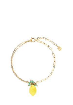 Bracelet en or avec deux styles de chaîne et un pendentif citron jaune orné de petites perles vertes sur un fond blanc.