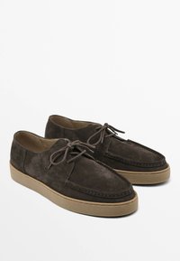 Brown suede shoes featuring a rounded toe, lace-up closure, and a textured rubber sole for grip. Simple stitching accents the design.