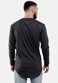 Langarmshirt in donkergrijze stof met een relaxte pasvorm. Heeft een ronde zoom en een subtiele logo-detail op de achterkant van de nek.