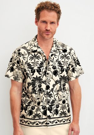 Kurzärmliges Hawaii-Hemd in Creme mit kräftigen schwarzen Blumen- und Blattmustern, ausgestattet mit durchgehender Knopfleiste und entspanntem Kragen.