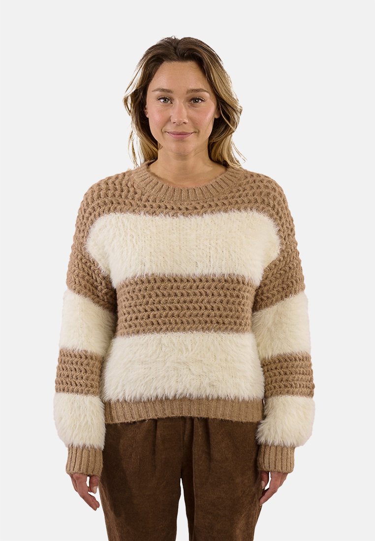 Maglione a righe marroni e crema con un motivo di maglia texturizzato, filato peloso e polsini a coste. Indossato con pantaloni marroni per creare un contrasto.
