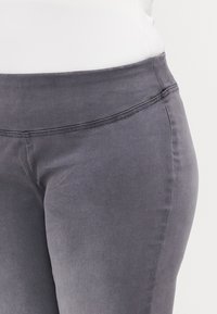 Gray denim pants with a high waistband, smooth texture, and decorative stitching along the waistline and side seams.