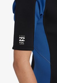 Krótki pianka z krótkimi rękawami, wykonana z czarnego i niebieskiego neoprenu, z widocznym logo i teksturą, oznaczona jako 2/2mm Foil Series.