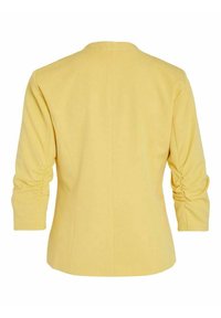 Keltainen bleiseri, jossa on sileä pinta, pyöreä kaula-aukko, kolmannen osan hihat ja laskostukset hihoissa.