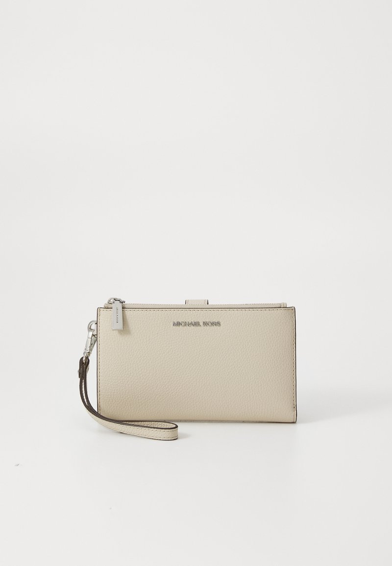 Beige skinnlommebok med teksturert overflate, med en sølvfarget logo og et avtakbart håndleddstropp. Rektangulær form med glidelås.