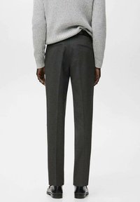 Pantaloni sartoriali grigi a taglio slim, caratterizzati da una texture liscia e sottili righe verticali, abbinati a scarpe nere.