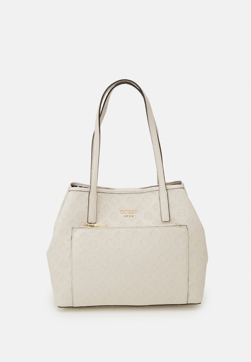 Sac cabas Guess beige avec motif de logo en relief, poche zippée à l'avant et double poignées d'épaule sur fond blanc.
