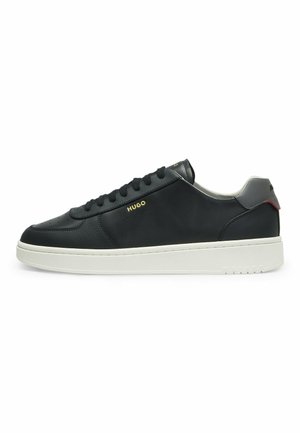 Black low-top leather sneaker with white sole, black laces, perforated details, gray heel tab, and gold "HUGO" logo on the side.