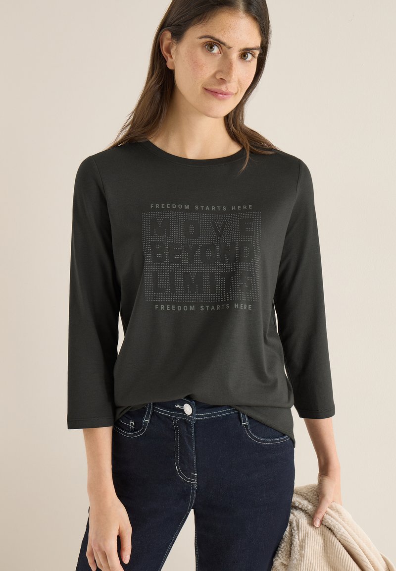 Schwarzes Langarm-T-Shirt mit Rundhalsausschnitt, verziert mit einem Textgrafik "MOVE BEYOND LIMITS" und "FREEDOM STARTS HERE" in einem strukturierten Design.