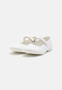 Bílé boty Mary Jane s plochou podešví, kulatou špičkou a jedním nastavitelným páskem přes nárt, s hladkým povrchem.
