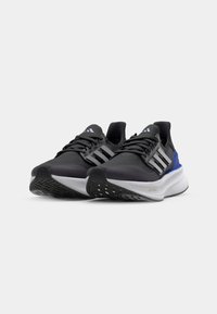 Black athletic shoes with light gray sole and blue accents. Features three white stripes, textured upper, and cushioned outsole.