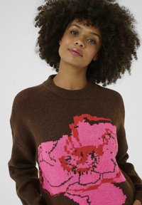 Brown knitted sweater with a large pink floral design on the front. Features a round neckline and long sleeves. Soft texture.