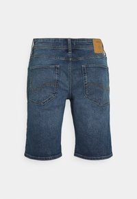 Bermudas de mezclilla de color azul oscuro, de longitud por encima de la rodilla, con dos bolsillos traseros y costuras curvas, además de una etiqueta de cuero marrón en la cintura.
