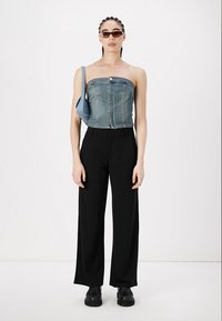 Denim top bez naramenica; tamnoplava, uska silueta s prednjim dugmetom. Crne široke hlače; glatka tkanina, bočne džepove. Crne cipele na debelu petu.
