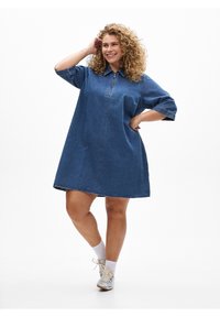 Farkkumekko, jossa on vetoketjullinen pääntie, lyhyet hihat, väljä istuvuus ja kellomainen malli. Kangas on keskisininen ja sileäpintainen.