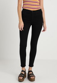 Svarta slim fit-jeans med hög midja, med klassisk femfickdesign och subtila sömmar. Matchas med svarta plattformssandaler.