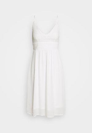 Weißes Kleid mit dünnen verstellbaren Trägern, V-Ausschnitt, strukturiertem besticktem Oberteil und fließendem Rock. Hergestellt aus leichtem Stoff.