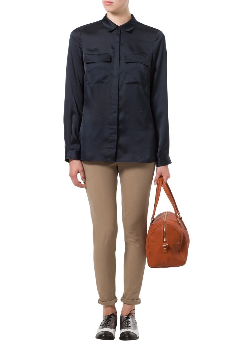 Námořnická saténová košile s dlouhým rukávem a knoflíkovým zapínáním, se dvěma kapsami na hrudi, v kombinaci s světle khaki vypasovanými kalhotami a hnědou koženou kabelkou. Černobílé boty.