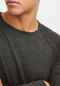 Diepgrijze, langemouwen shirt van een gestructureerde breiselstof. Het shirt heeft een ronde halslijn en raglanmouwen.