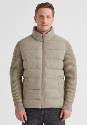 Helle khakifarbene Puffer-Weste mit hohem Kragen, die gesteppten Vorderseiten und strukturierte Strickärmel aufweist. Mit Reißverschluss und zwei seitlichen Taschen.