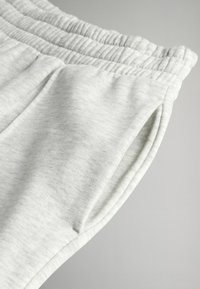 Lys grå sweatpants lavet af blødt, struktureret stof. Har en elastisk talje og sidelommer med en afslappet pasform.