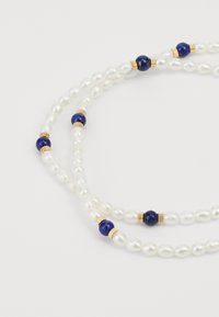 Collar de doble hebra con perlas blancas, intercaladas con cuentas azules y acentos dorados, que ofrece una textura suave y formas variadas.