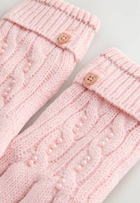 Rosa gestrickte Beinstulpen mit einem Kabelmuster, verziert mit Perlenakzenten und einem Bündchen mit einem herzförmigen Knopf sowie metallischen Fäden.
