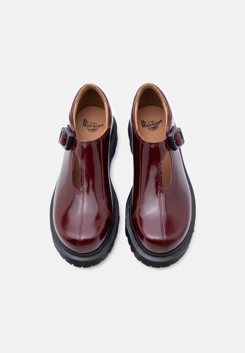 Chaussures en cuir verni bordeaux avec un design à bride en T, dotées d'une boucle réglable et d'une semelle extérieure épaisse en caoutchouc noir.