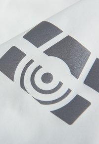 Vit tyg med en stor grå grafisk design som har rundade former och koncentriska cirklar, vilket betonar ett modernt geometriskt mönster.