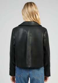 Veste en cuir noire avec un large col et un design court. Texture lisse, style minimaliste et coupe sur mesure ; détails de couture visibles.