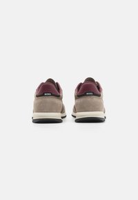 Baskets en daim beige avec accents bordeaux au talon et œillets noirs. Elles disposent d'une semelle en caoutchouc crème et du logo « BOSS » sur le talon arrière.